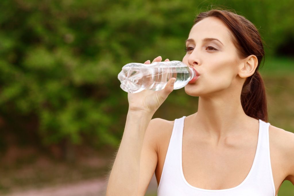 Eine Frau trinkt Wasser aus einer Flasche