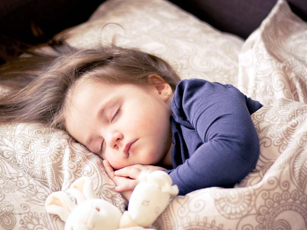 Ein kleines Mädchen schläft auf einem Bett