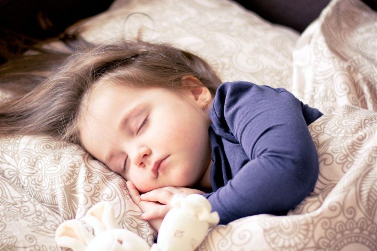 Ein kleines Mädchen schläft auf einem Bett
